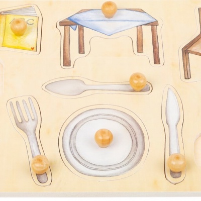 mini peças de madeira ilustrando uma mesa posta com talheres, cadeiras, jarro e fruta