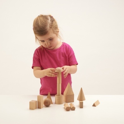 Criança a brincar com blocos de madeira sobre mesa branca