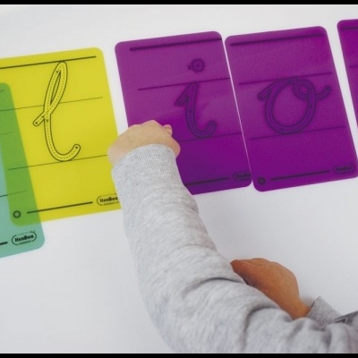 Cartões coloridos com letras cursivas e uma mão de criança a interagir