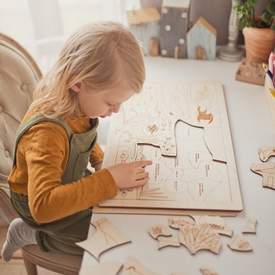 Criança a montar puzzle de madeira numa mesa numa sala iluminada