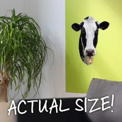 Decoração de parede cabeça de vaca preta e branca com sino na parede verde-limão junto a planta e sofá