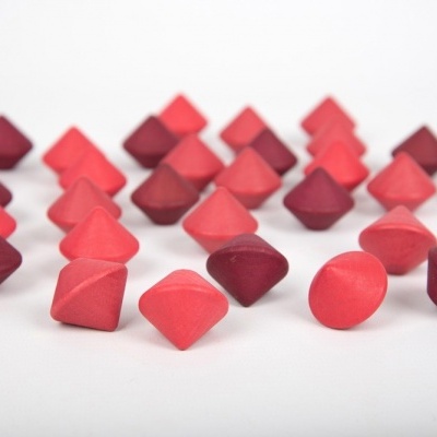 Peças de jogo geométricas vermelhas, vinho e rosa sobre fundo branco