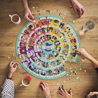 Quebra-cabeças redondo com ilustrações de mulheres e texto WOMEN em centro, mãos a montar, canecas e copo na mesa