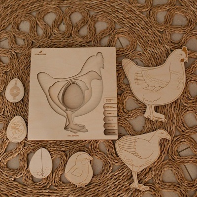 Peças de madeira representando uma galinha e ovos, sobre base trançada de fibra natural