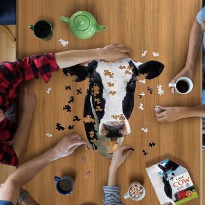 Mesa com puzzle da cabeça de uma vaca e várias chávenas, pacote 'I AM COW'