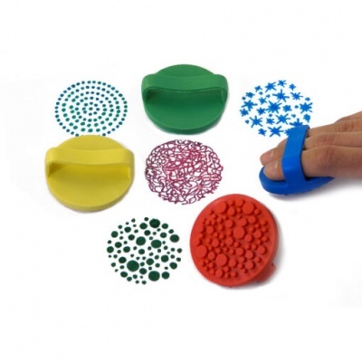 Cinco carimbos coloridos de silicone com padrões variados e uma mão a usar um carimbo azul