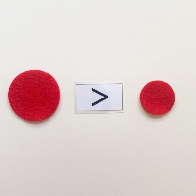 Dois círculos vermelhos de feltro com etiqueta de sinal '>' entre eles