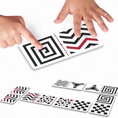Cartas com padrões geométricos em preto, branco e vermelho e duas mãos a tocar nas cartas.