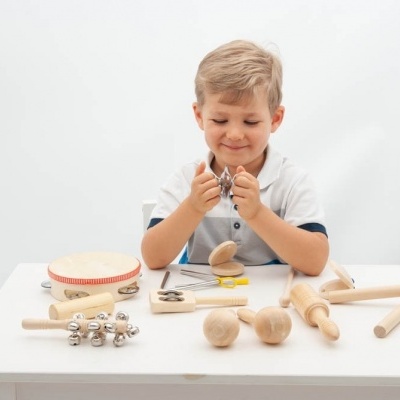 Criança a tocar brinquedos musicais de madeira numa mesa branca