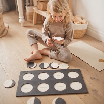 Criança brincando com jogo de memória de fases da lua em madeira colorida.