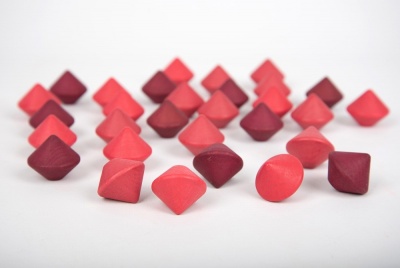 Peças de jogo geométricas vermelhas, vinho e rosa sobre fundo branco