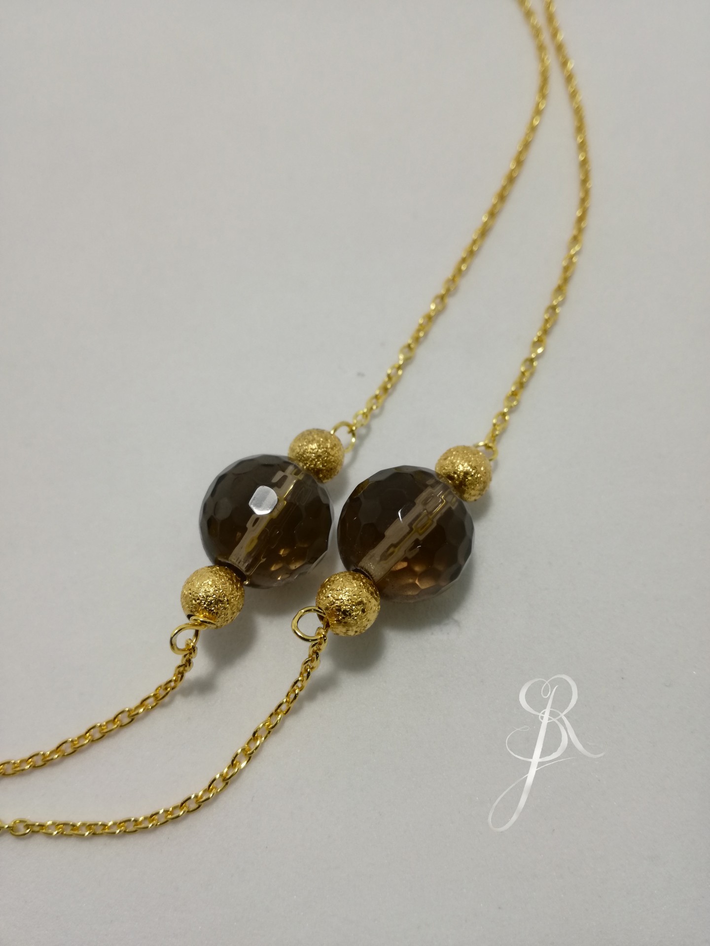 Colar Quartz Fume e Granitos Colar dourado com pendentes esféricos castanhos escuros e textura detalhada