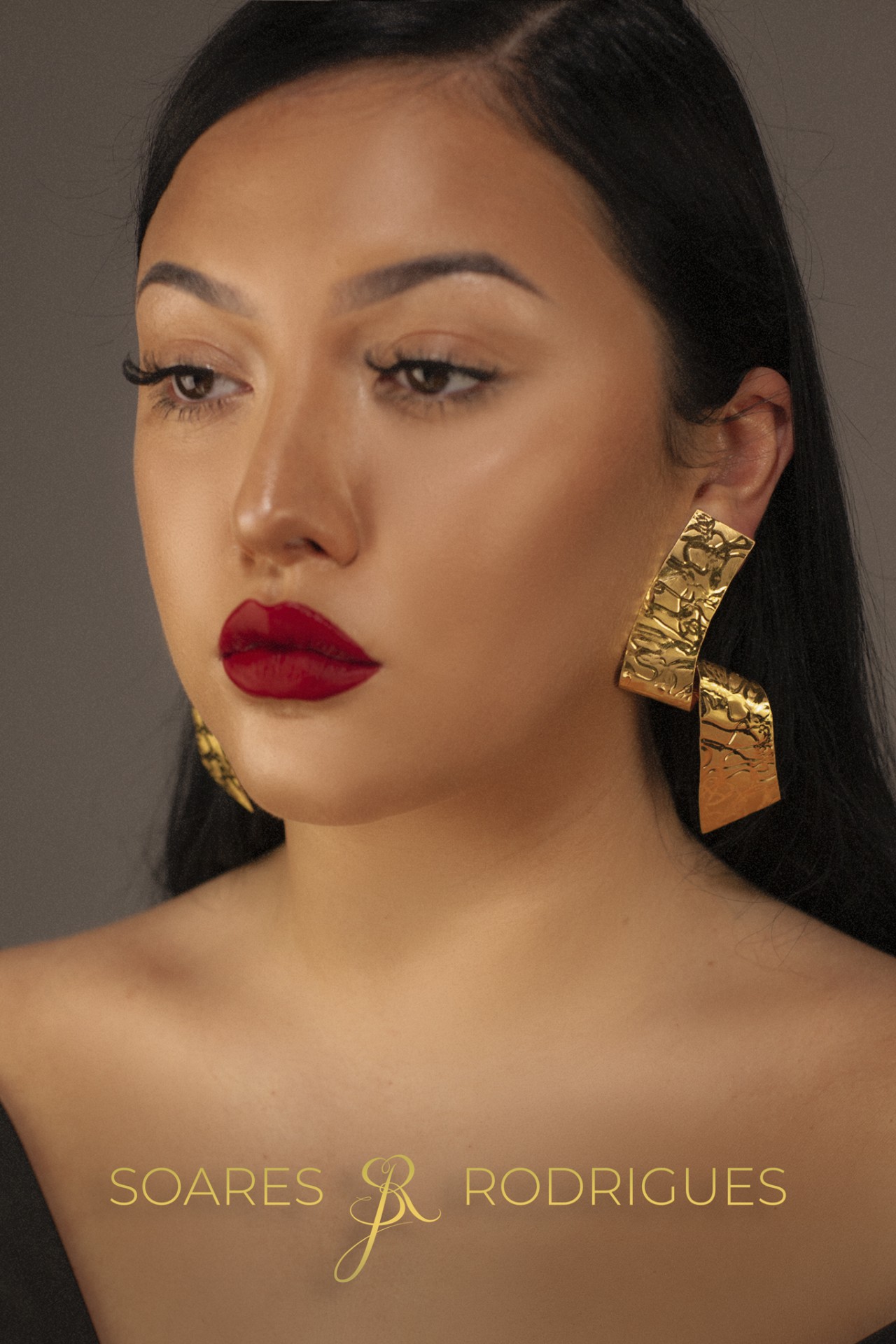 Brincos Samurai Brincos dourados grandes e texturizados usados por mulher com batom vermelho