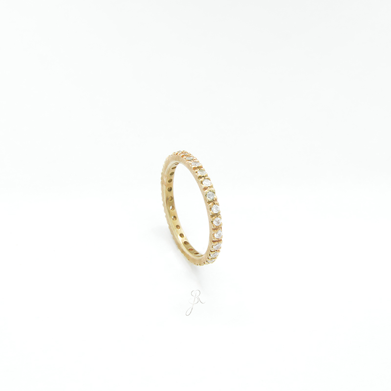 Aliança de Zircónias Anel de ouro amarelo com pedras transparentes ao longo da circunferência em fundo branco