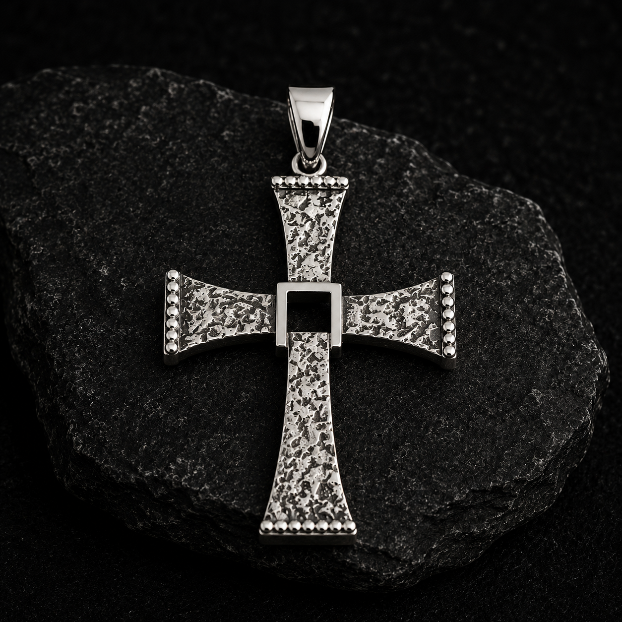 Cruz Rústica Pendente em forma de cruz prateada com textura rugosa sobre pedra escura