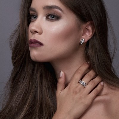 Mulher com brincos e anel prateados com pedras quadradas