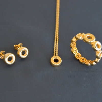 Conjunto de joalharia com brincos, colar e anel dourados com padrão de círculos vazados