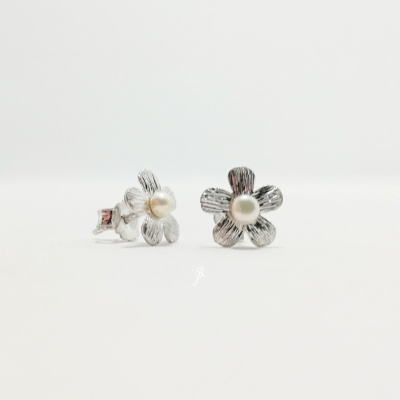 Brincos de pérola em forma de flor com pétalas prateadas.