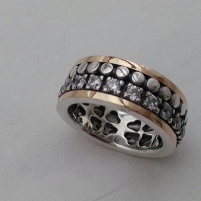 anel bicolor com pedras brilhantes e padrão em metal preto