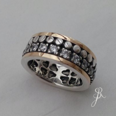 anel de metal prateado e dourado com pedras brilhantes e detalhes metálicos