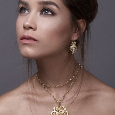 Mulher a usar conjunto de colar e brinco dourados com design em filigrana