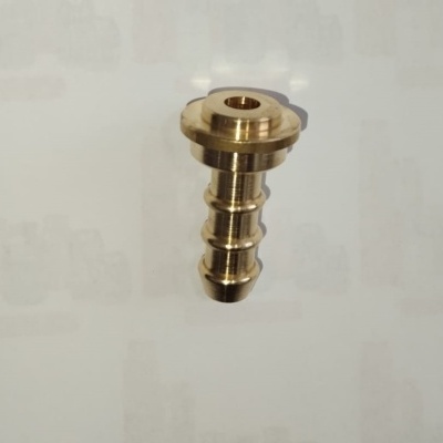 Peça metálica dourada com forma cilíndrica e orifício no topo sobre fundo branco