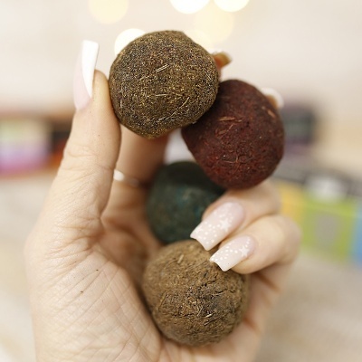 Mão segurando bolas fibrosas coloridas em fundo desfocado