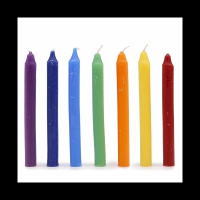 Sete velas coloridas em pé, alinhadas em linha sobre fundo branco