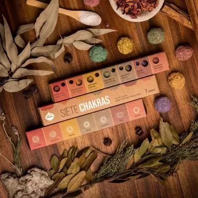 Caixas coloridas de incenso Siete Chakras com bolas aromáticas e folhas secas sobre madeira
