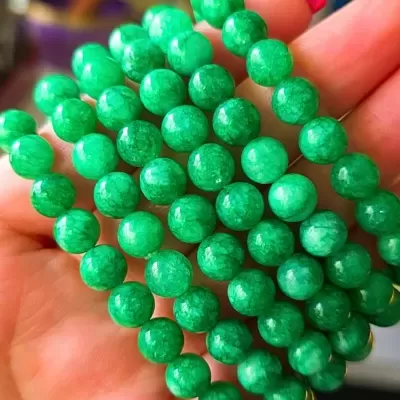 Pulseira de contas verdes na mão com unha vermelha