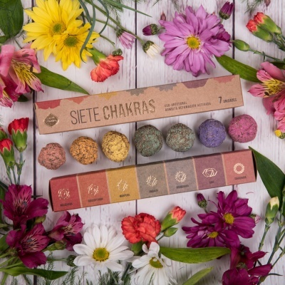 Conjunto de 7 incensos naturais para chakras com caixa castanha rodeado por flores coloridas