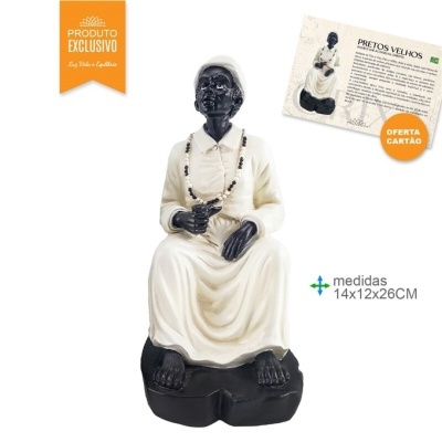 Estátua de figura humana sentada com pele preta, roupa branca e colar de contas