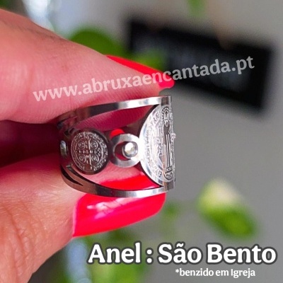 Anel de metal com símbolos de São Bento segurado por uma mão com unhas vermelhas