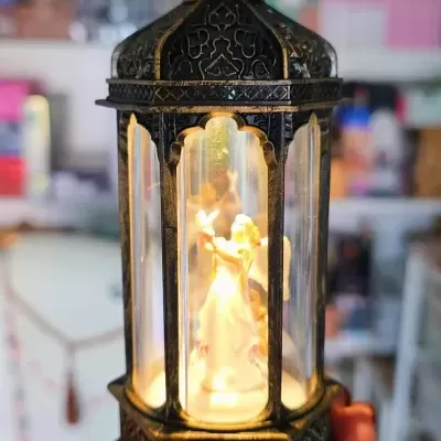 Lanterna decorativa de metal com vidro e anjo iluminado dentro