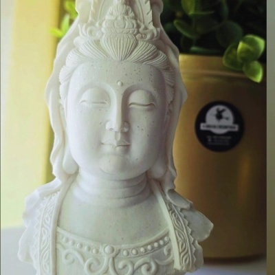 Busto branco de Kuan Yin com planta ao fundo