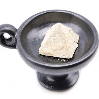 Taça preta com cabo contendo pó amarelo claro