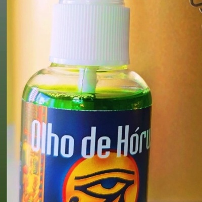 Frasco verde com spray e rótulo azul com texto e símbolo egípcio