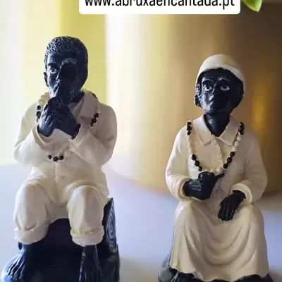 Estatuetas cerâmicas de figuras humanas sentadas, roupas brancas, colares de contas, base preta.