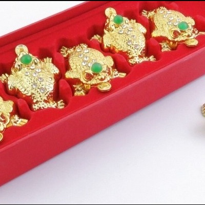 Casticais dourados com pedras verdes numa caixa vermelha
