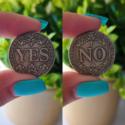 Moedas metálicas decorativas com YES e NO, seguradas por dedos com unhas azuis, fundo de planta verde