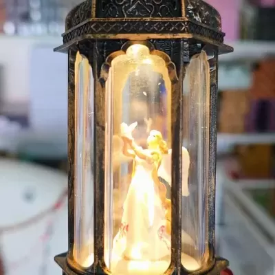 Lanterna decorativa com figura de anjo iluminada dentro
