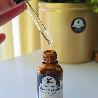 Frasco âmbar com conta-gotas para serum capilar junto a planta verde.