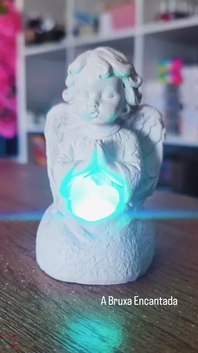Estátua de anjo em resina branca com luz azul entre as mãos em oração