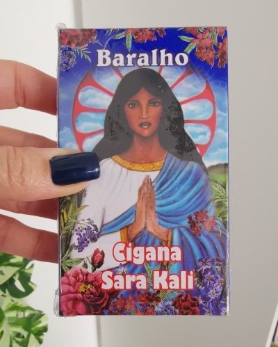 Caixa de baralho com ilustração feminina e texto Baralho Cigana Sara Kali