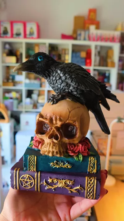 Estatueta de corvo sobre crânio e livros decorativos coloridos.