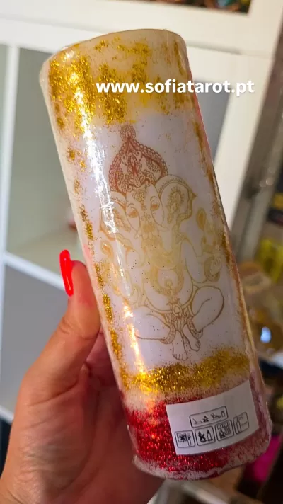 Vela branca decorada com glitter dourado e vermelho e desenho de Ganesha