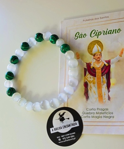 Pulseira verde e branca ao lado de cartão e autocolante relacionados a São Cipriano.