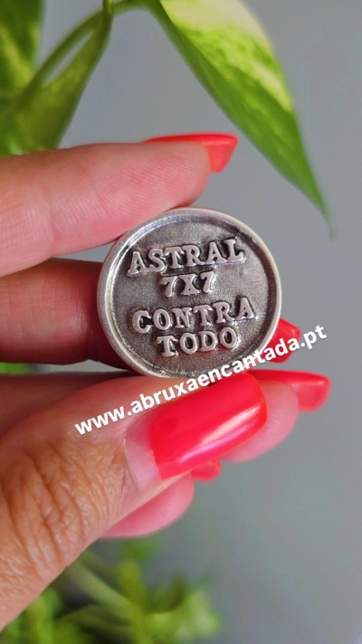 Moeda metálica redonda com inscrições em relevo segurada entre dedos com unhas vermelhas