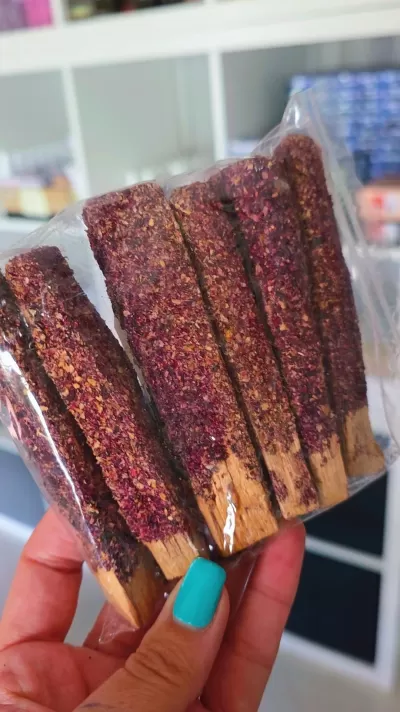 Mão com unhas azuis segura pauzinhos cobertos em pó roxo