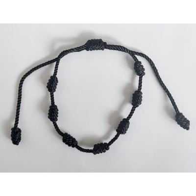 Pulseira preta trançada com nós decorativos sobre fundo branco